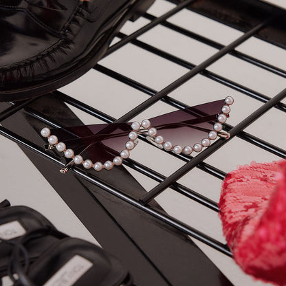 still life of emily in paris x diff eyewear featuring the mindy 2.0 cateye sunglasses with a champagne pearl frame and grey gradient lenses next to accessories and shoes