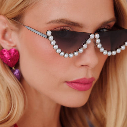 lifestyle - female trying on emily in paris x diff eyewear featuring the mindy 2.0 cateye sunglasses with a champagne pearl frame and grey gradient lenses angled view