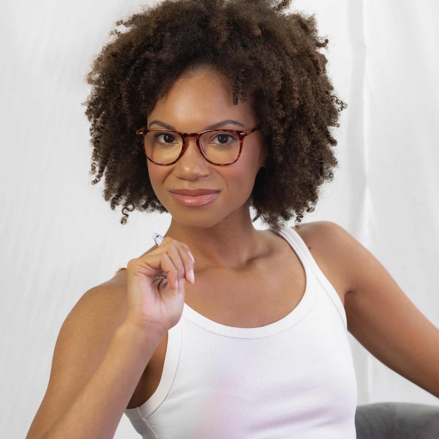 brunette model wearing the griffin in amber tortoise and blue light readers