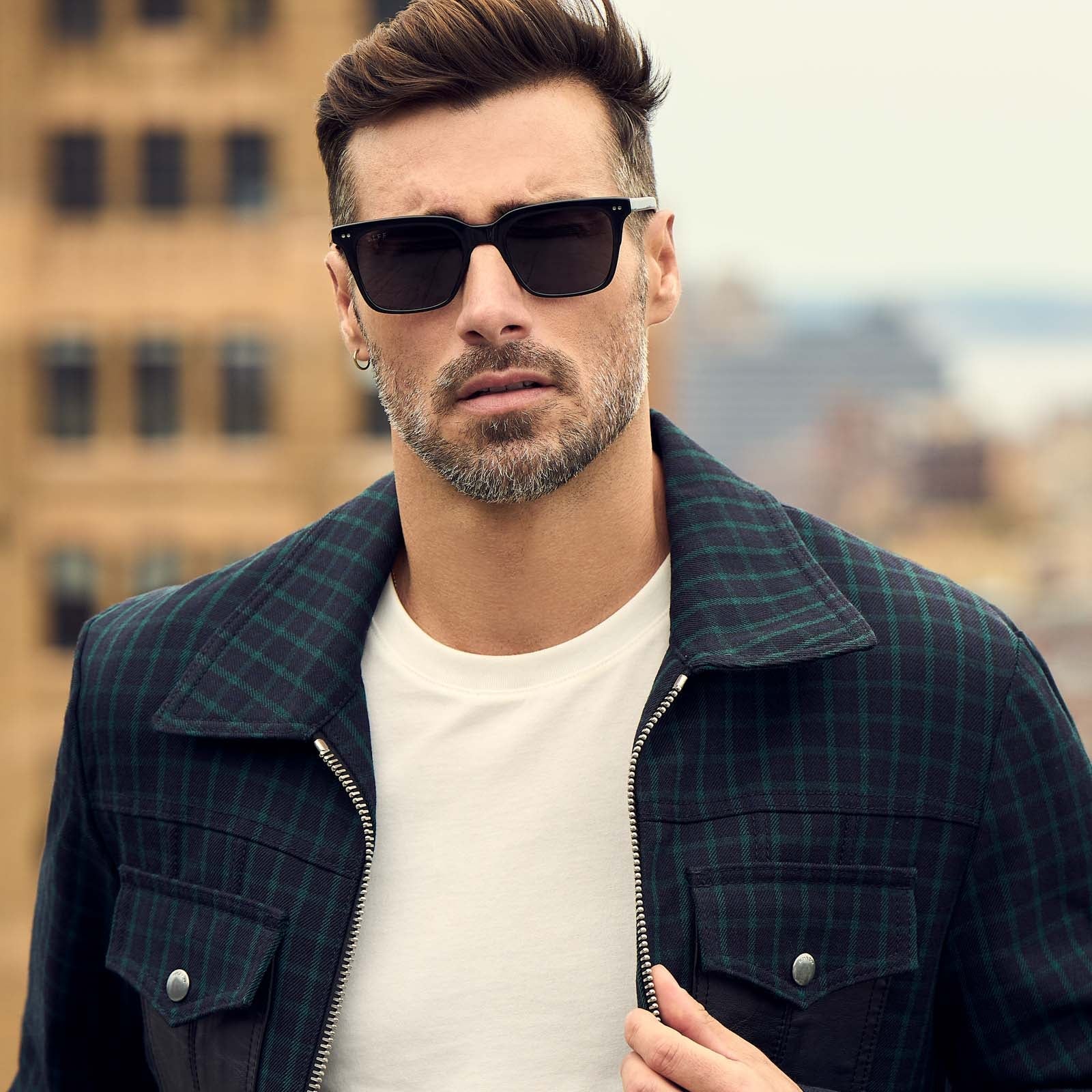 on model - male gazing at the camera while wearing the diff eyewear billie square sunglasses with a black acetate frame and grey polarized lenses