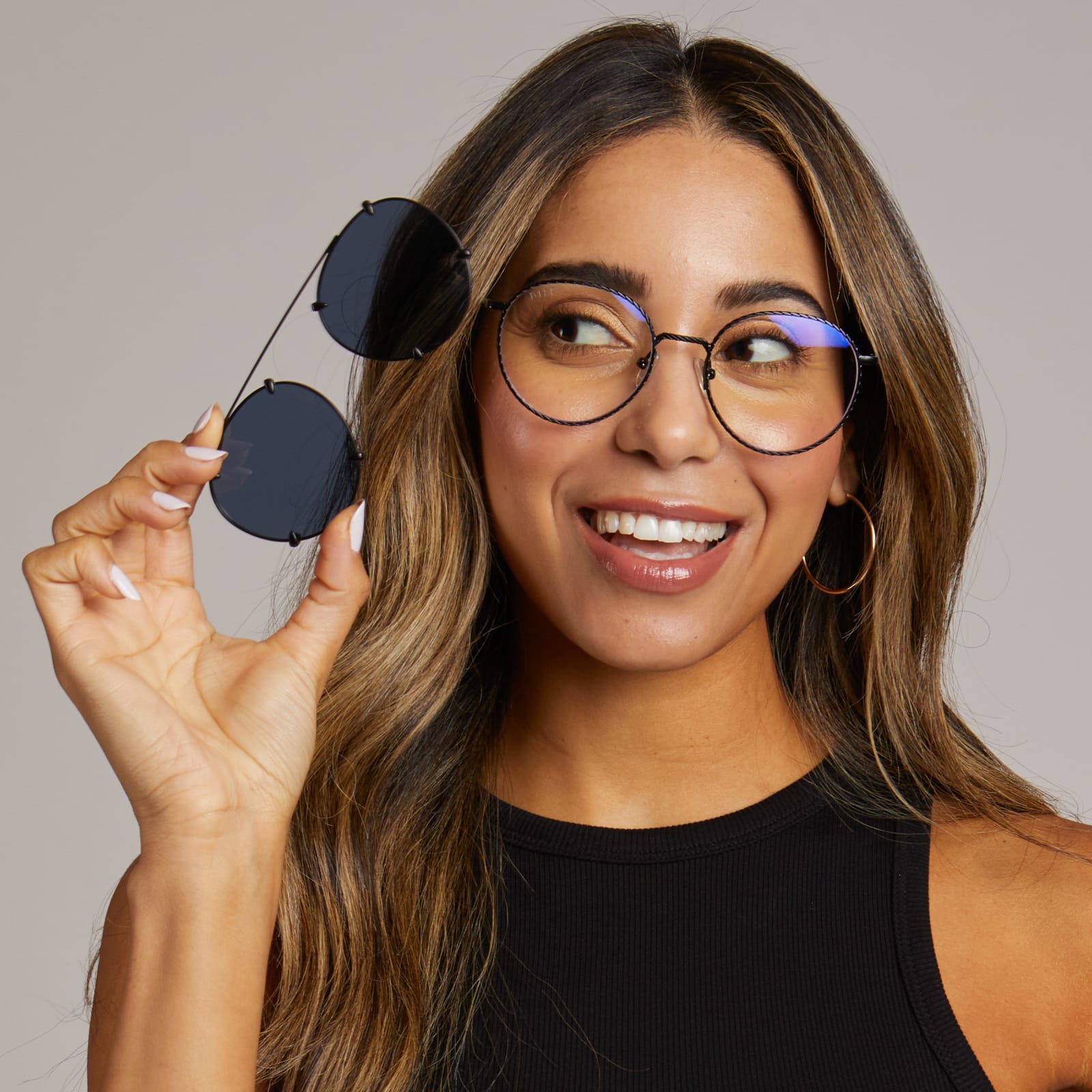on model - diff eyewear x harry potter female wearing ravenclaw glasses with a scholarly matte black frame and prescription lenses while holding ravenclaw sunglasses with a scholarly matte black frame and twighlight blue lenses