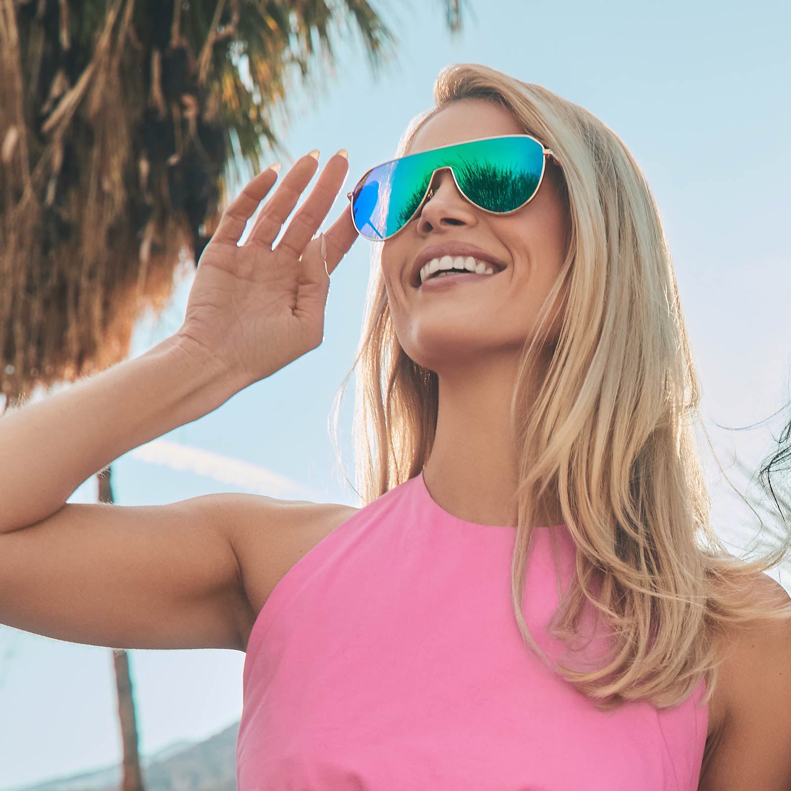 on model - female leaning on a wall wearing diff eyewear dash shield oversized sunglasses with a gold metal frame and green mirror lenses front view