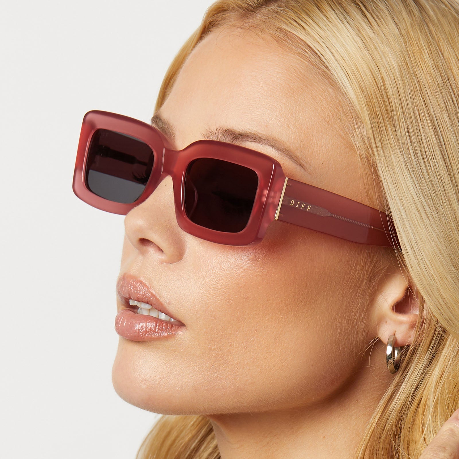 on model - blonde female wearing diff eyewear featuring the indy rectangle sunglasses with a guava pink frame and grey lenses