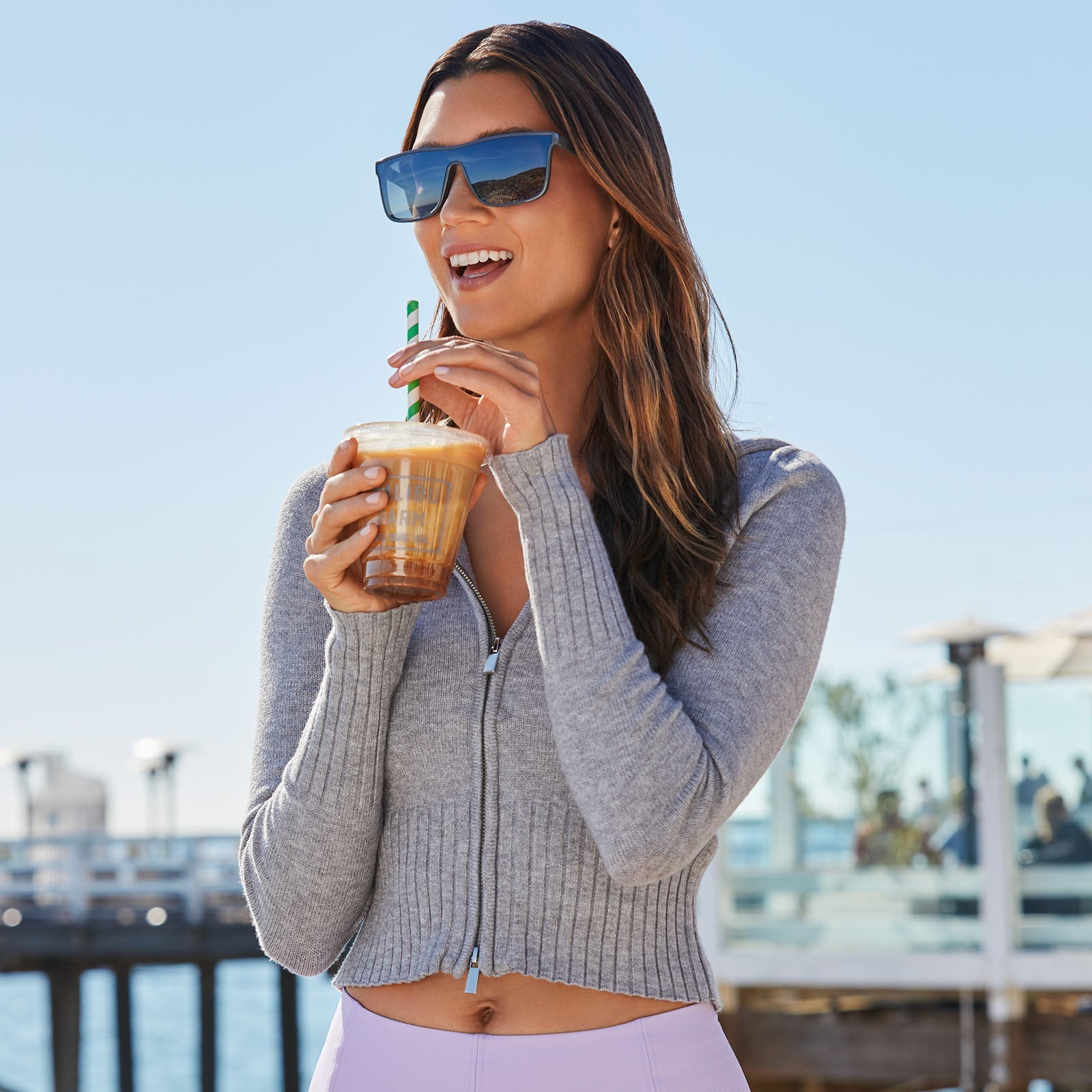 lifestyle - female drinking coffee wearing diff sport flash square sunglasses with a slate grey frame and grey gradient with silver flash polarized lenses front view