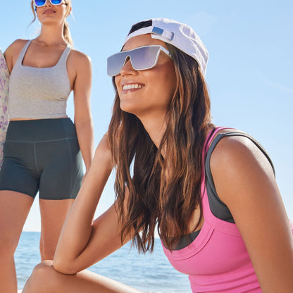 lifestyle - female sitting on the beach wearing diff sport flash square sunglasses with a silver frame and peach mirror polarized lenses front view