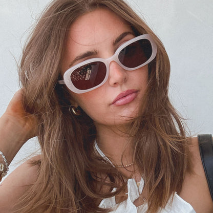 lifestyle - aspyn ovard x diff eyewear female wearing the cove oval sunglasses with a milky blush frame and brown lenses front view