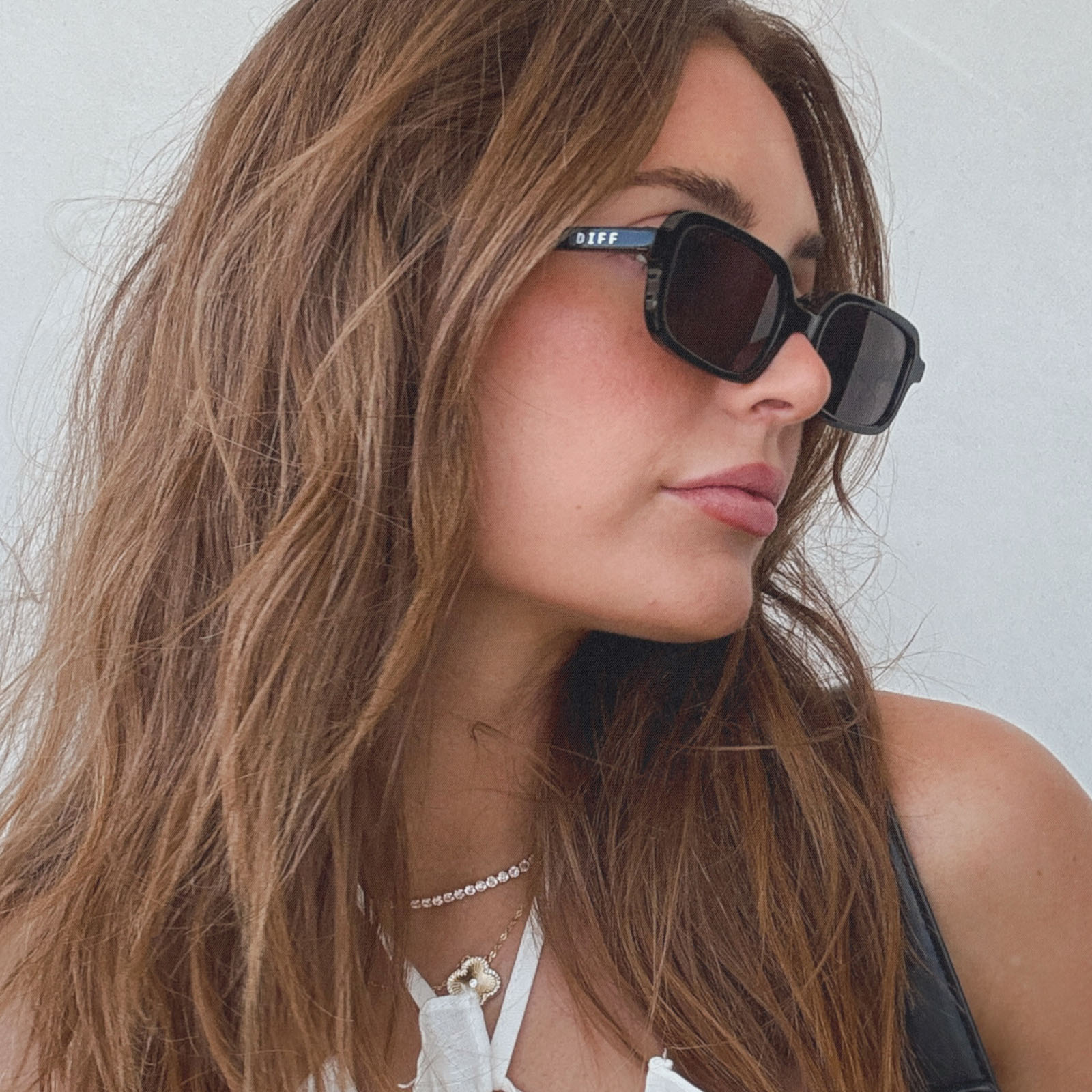 lifestyle - aspyn ovard x diff eyewear female wearing the elle rectangle sunglasses with a black frame and grey lenses side view