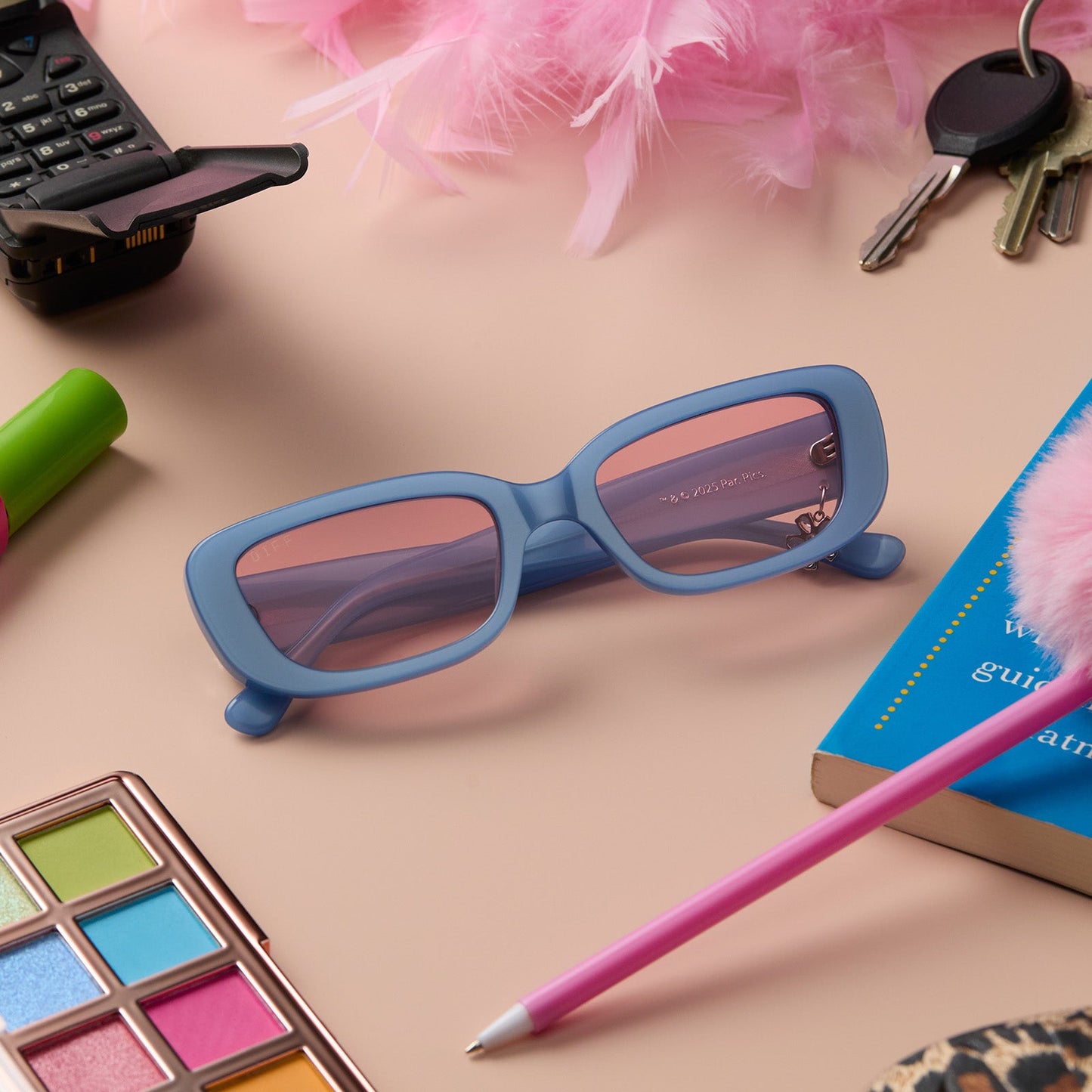 lifestyle - still life of clueless x diff eyewear featuring the cher round sunglasses with a light blue frame and pink gradient lenses front view