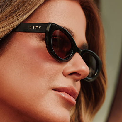 lifestyle - female jojo fletcher wearing diff eyewear jordy round cat eye sunglasses with a black acetate frame and brown lenses detailed view