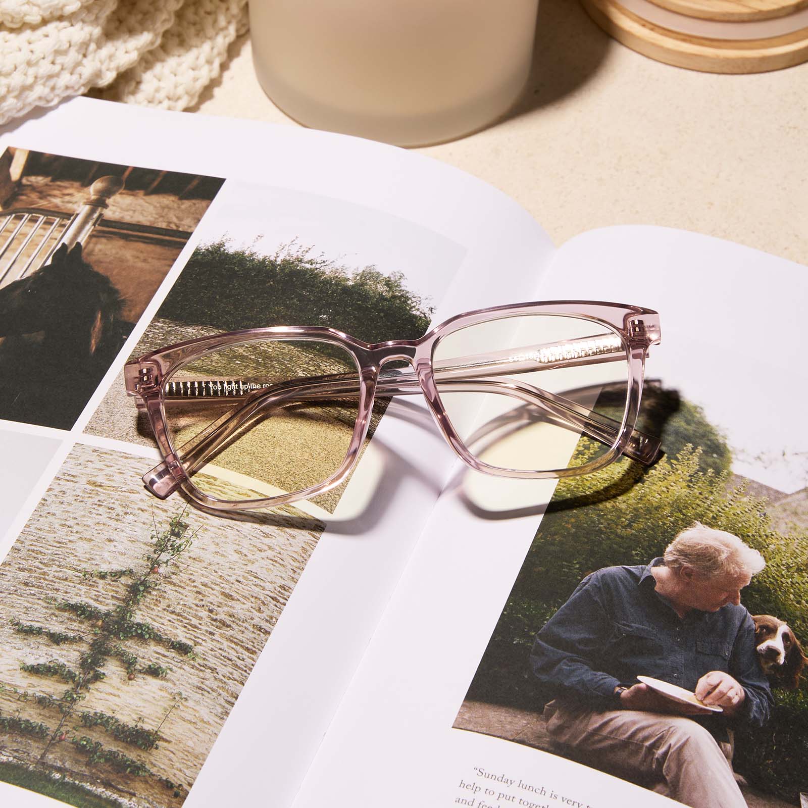 lifestyle - diff eyewear featuring the alex square blue light readers with a light pink crystal frame laying on a book