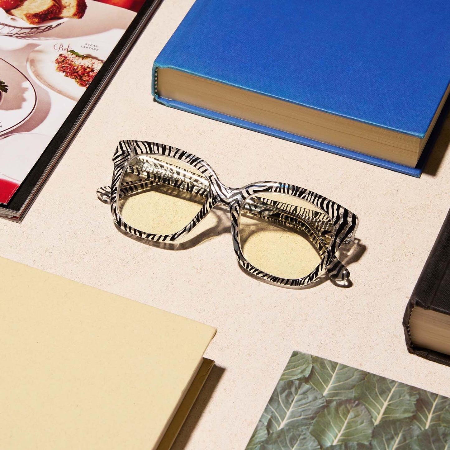 lifestyle - diff eyewear featuring the ava square blue light readers with a zebra frame on a desk