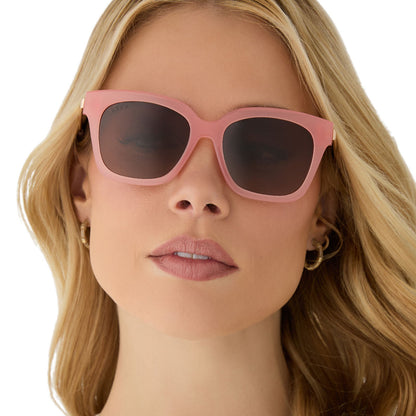 on model - female wearing diff eyewear featuring the bella xs square sunglasses with a peach frame and brown polarized lenses front view