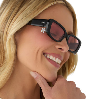 on model - female wearing clueless x diff eyewear featuring the cher round sunglasses with a black frame and pink gradient lenses angled view