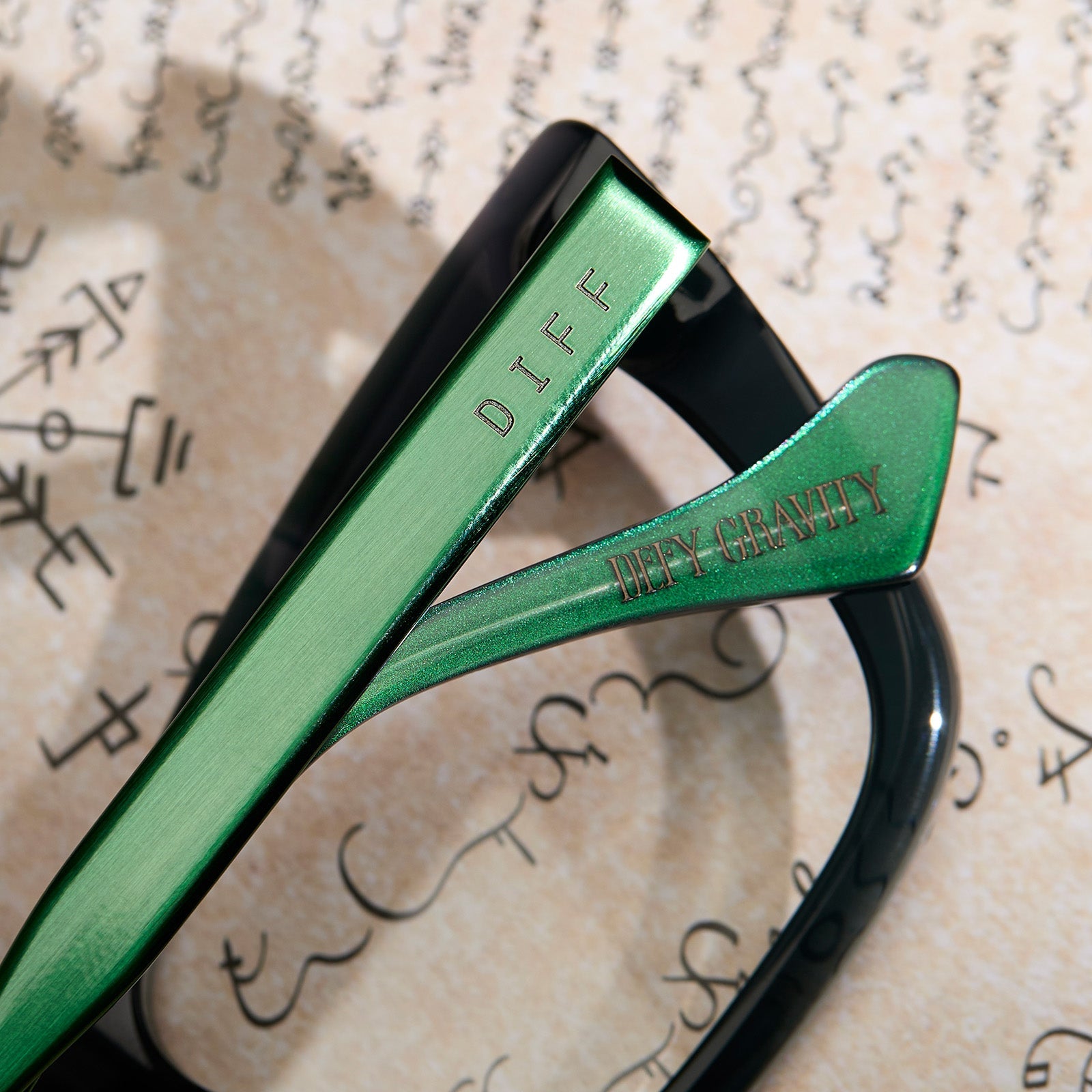 lifestyle - wicked x diff eyewear featuring the elphaba emerald square prescription glasses with a black green gradient frame detailed view of temple and temple tip with quote "Defy gravity"