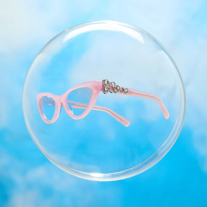 lifestyle - wicked x diff eyewear featuring the glinda upland for good cat eye prescription glasses with a pink frame floating in a bubble