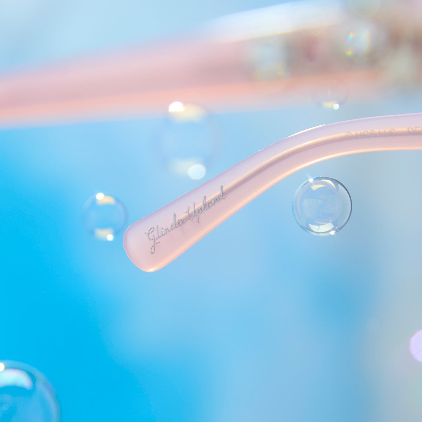 lifestyle - wicked x diff eyewear featuring the glinda upland for good cat eye prescription glasses with a pink frame detailed view of temple tip with Glinda Upland name