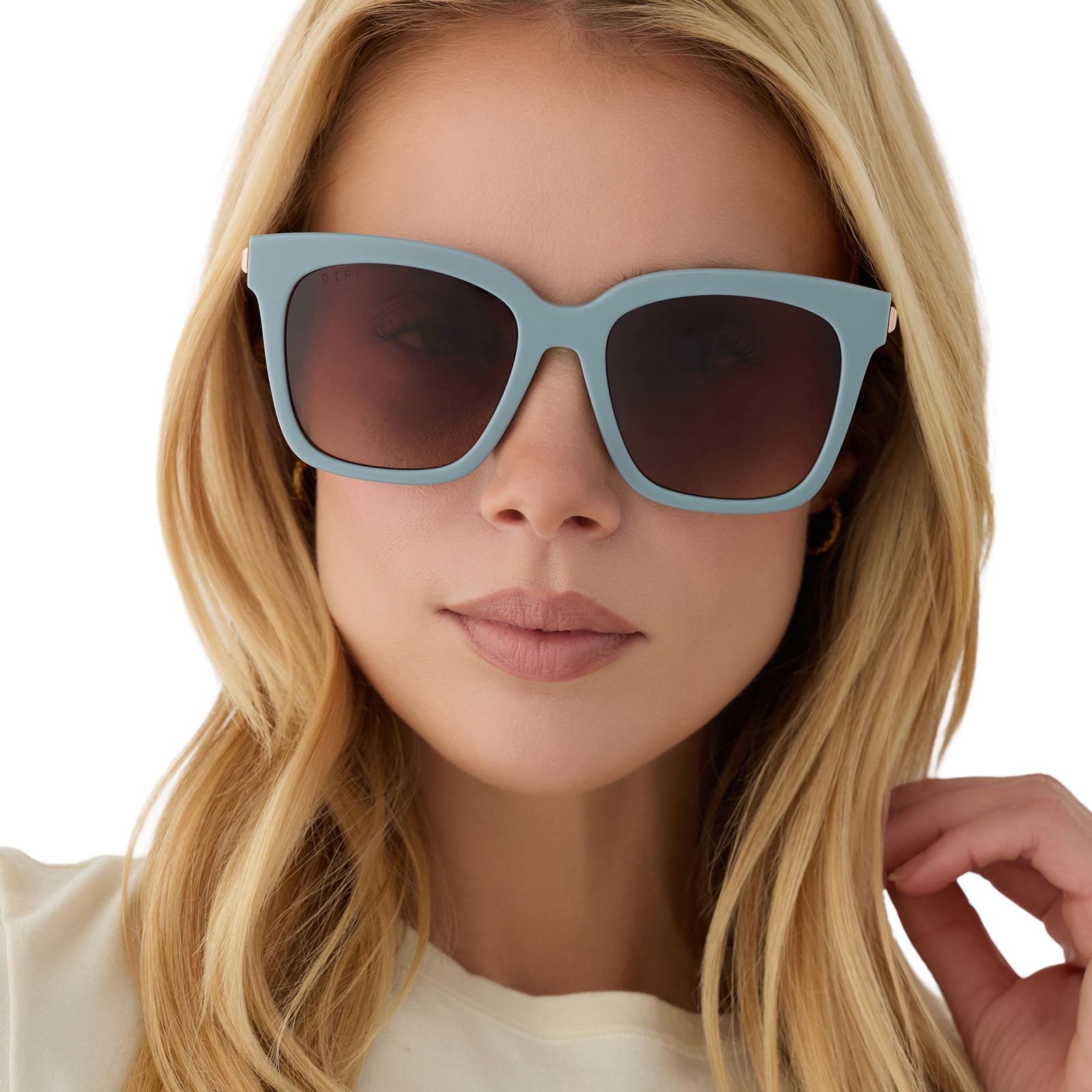 on model - blonde female wearing diff eyewear bella square oversized sunglasses with a dew drop blue frame, gold temples and brown gradient lenses front view