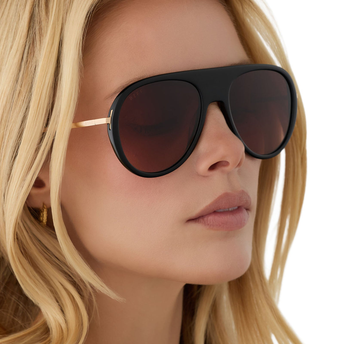 on model - blonde female wearing diff eyewear cleo oversized aviator sunglasses with a black frame, gold temples and brown gradient lenses angled view