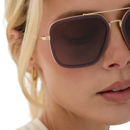 on model - blonde female wearing diff eyewear jordan navigator sunglasses with a cocoa powder brown frame, gold temples, and coca powder to baby blue gradient lenses detailed view