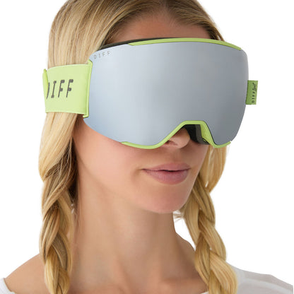 on model - female wearing diff sport alpine goggles in lime green with silver mirror polarized lens angled view