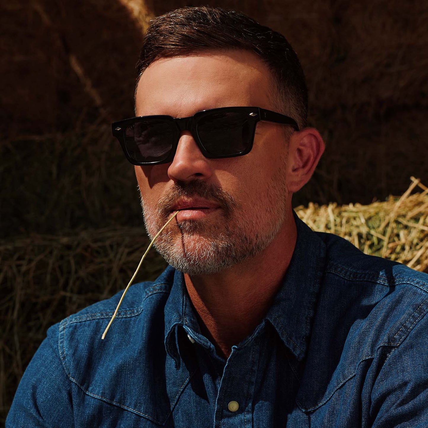 lifestyle - male cowboy wearing yellowstone x diff eyewear featuring the kayce dutton square sunglasses with a classic black acetate frame and grey polarized lenses front view