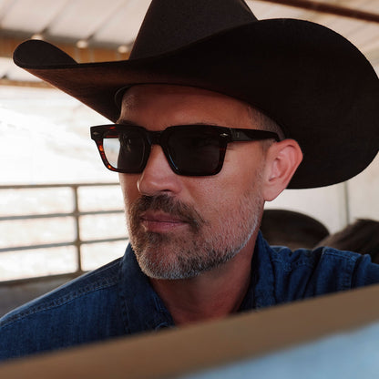lifesytle - male cowboy wearing yellowstone x diff eyewear featuring the kayce dutton square sunglasses with a western sequoia acetate frame and green g15 polarized lenses angled view