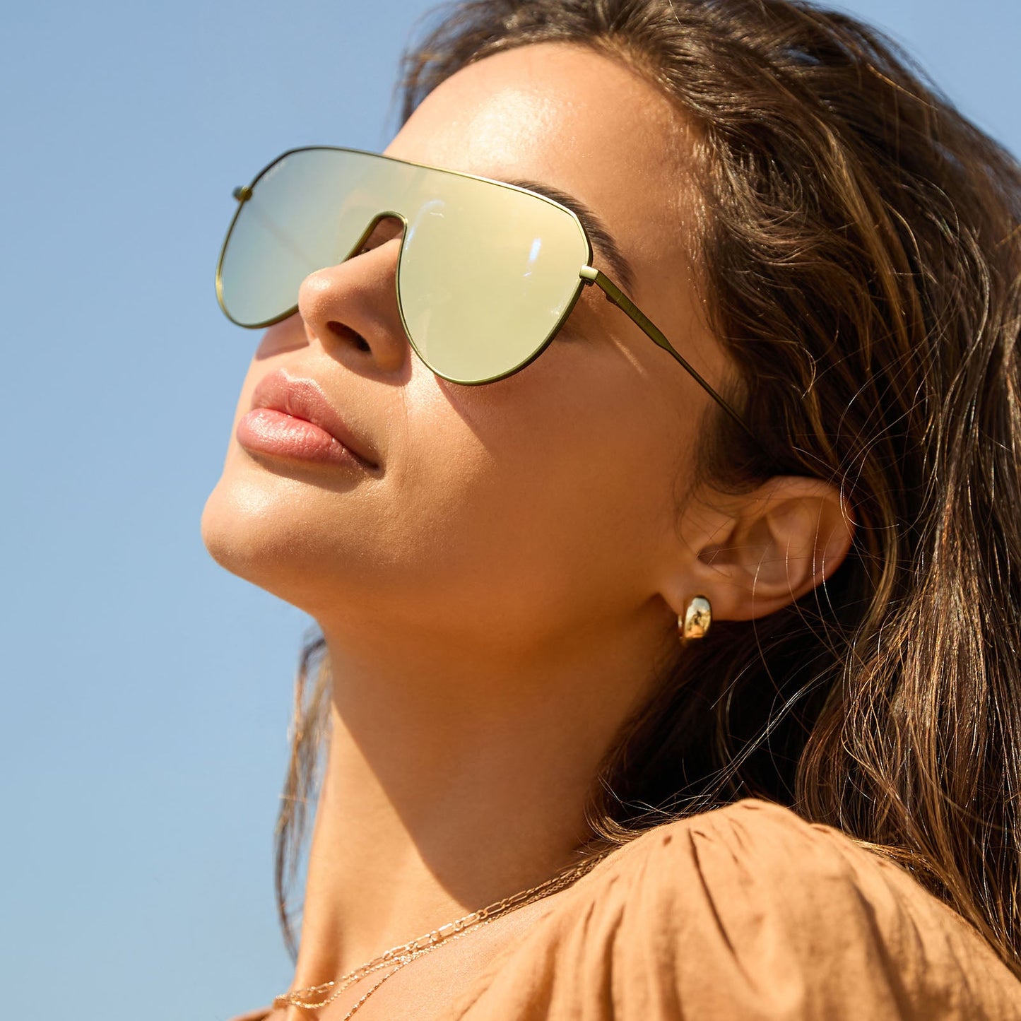 on model - female at the beach wearing diff eyewear featuring the dash shield shield sunglasses with a moss metal frame and moss mirror lenses angled view