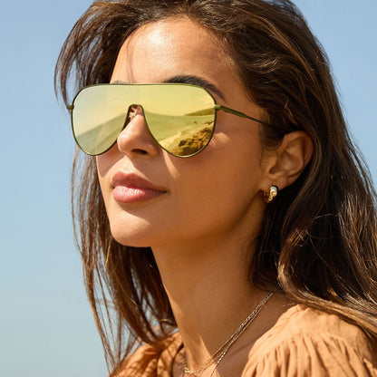 on model - female at the beach wearing diff eyewear featuring the dash shield shield sunglasses with a moss metal frame and moss mirror lenses front view