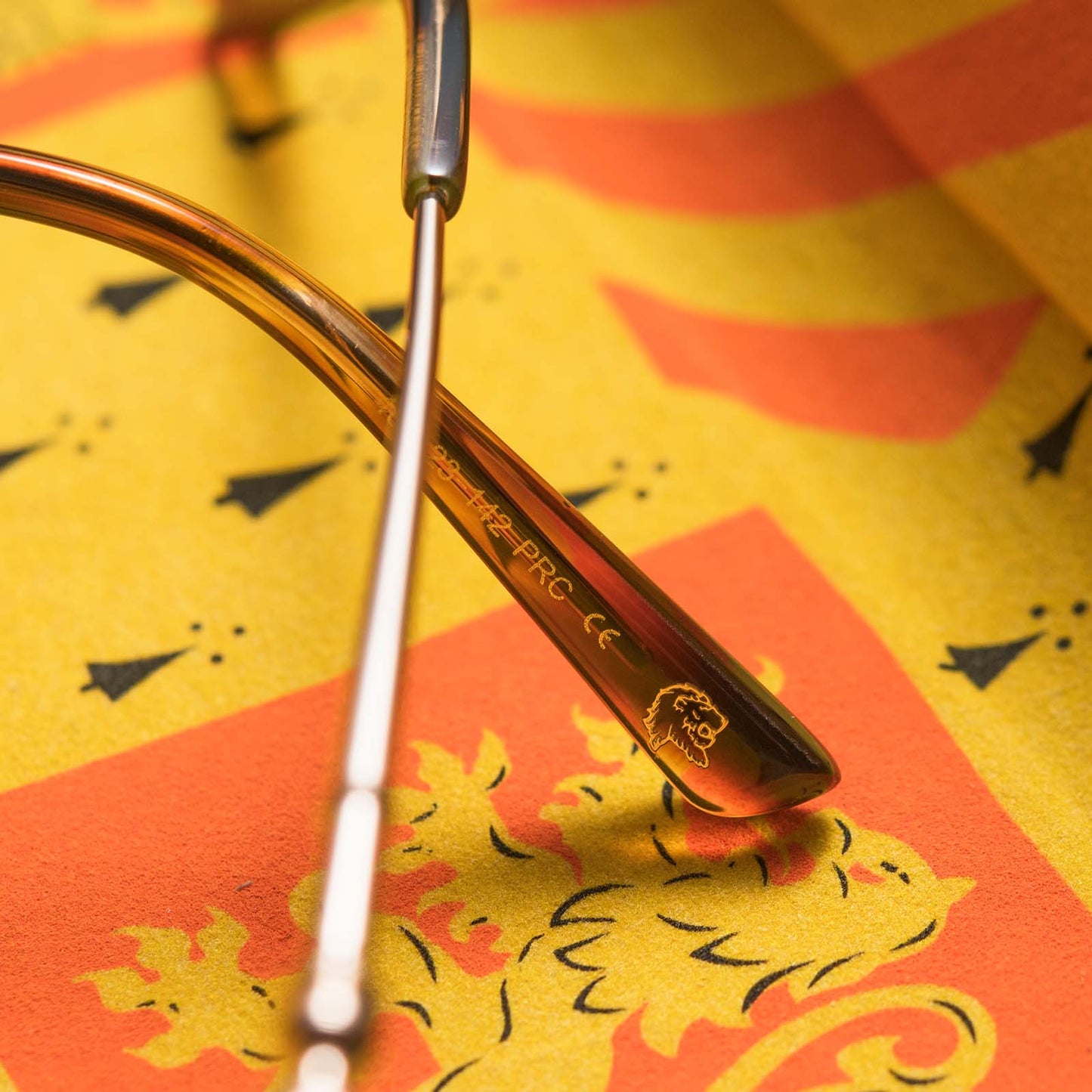 Close up of arm of Harry Potter x DIFF Gryffindor glasses with lions mane image engraved on top of yellow and orange case