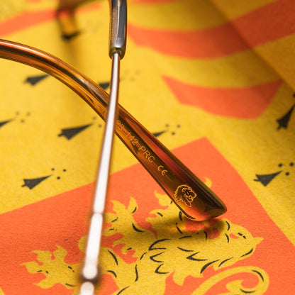 Close up of arm of Harry Potter x DIFF Gryffindor glasses with lions mane image engraved on top of yellow and orange case