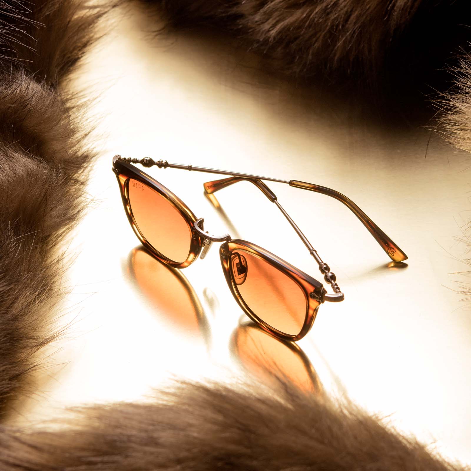 Flat-lay of Harry Potter x DIFF Gryffindor sunglasses lying half open upright  encircled by brown fabric