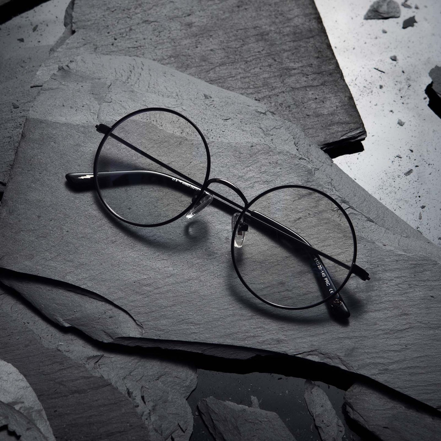Flat-lay of Harry Potter x DIFF Harry Potter glasses lying folded on top of black broken stone
