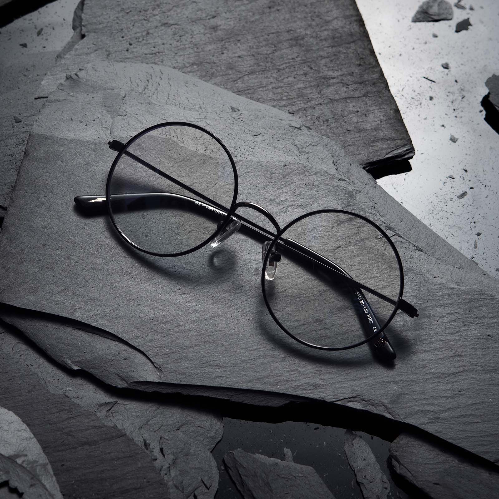 Flat-lay of Harry Potter x DIFF Harry Potter glasses lying folded on top of black broken stone