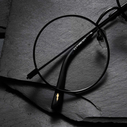 Close up of Harry Potter x DIFF Harry Potter glasses lying folded on top of black broken stone