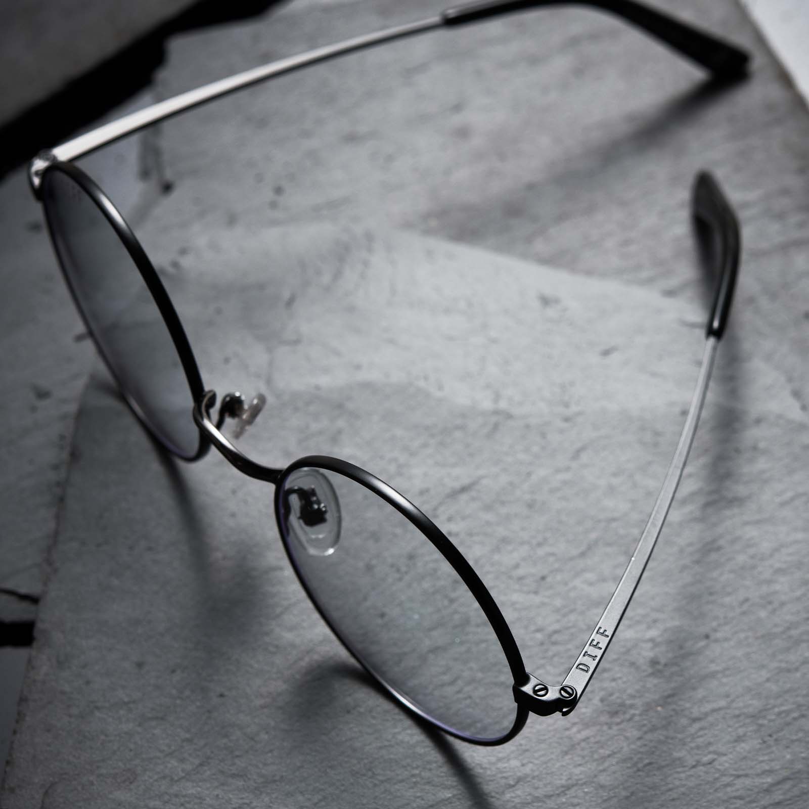 Harry Potter x DIFF Harry Potter glasses lying open on top of black broken stone