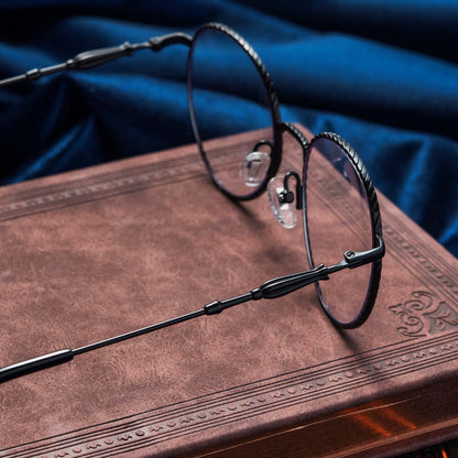 Harry Potter x DIFF Ravenclaw glasses lying open on top of book with blue fabric in the background