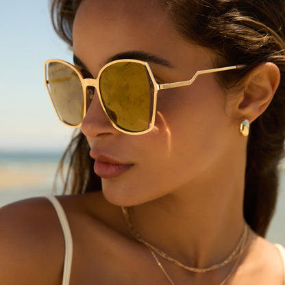 lifestyle - female wearing diff eyewear donna iii oversized square sunglasses with a gold metal frame and gold mirror polarized lenses side view