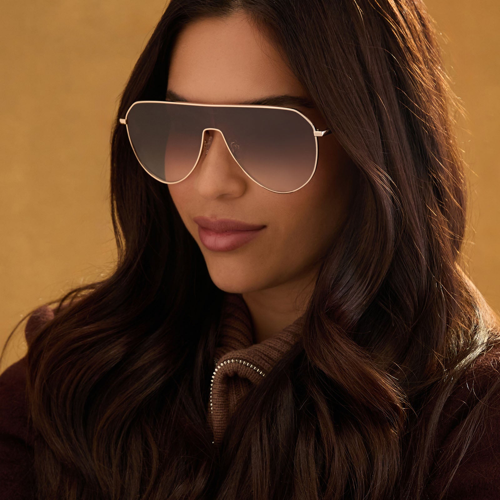 lifestyle - female wearing diff eyewear dash shield oversized sunglasses with a gold metal frame and brown gradient lenses front view