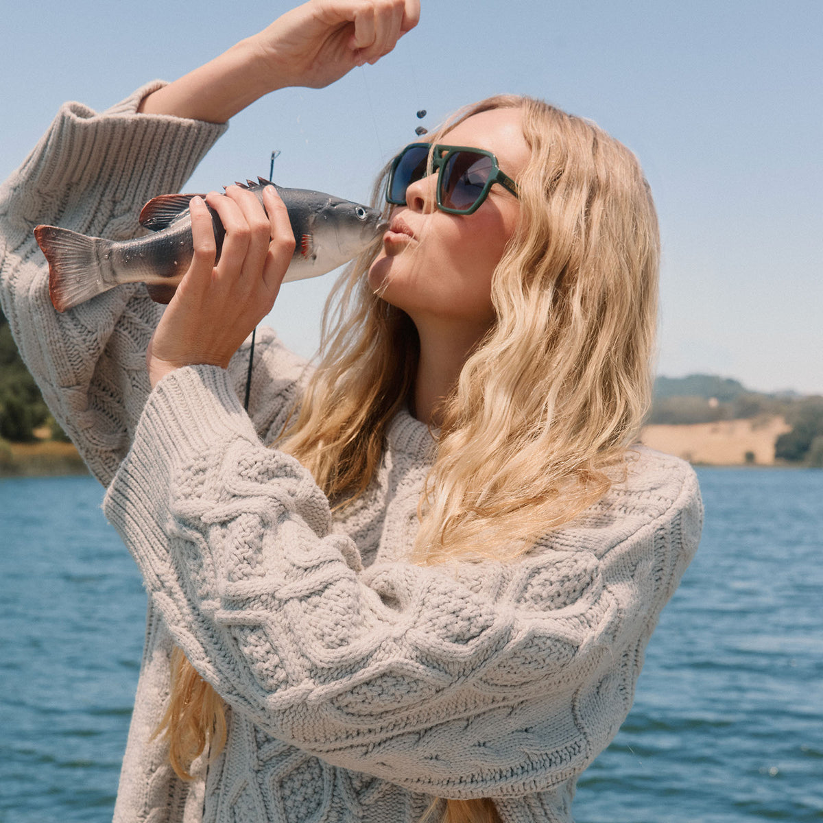 lifestyle - blonde female on a lake fishing wearing diff eyewear cameron navigator sunglasses in a fairway green acetate frame with grey gradient polarized lenses angled view