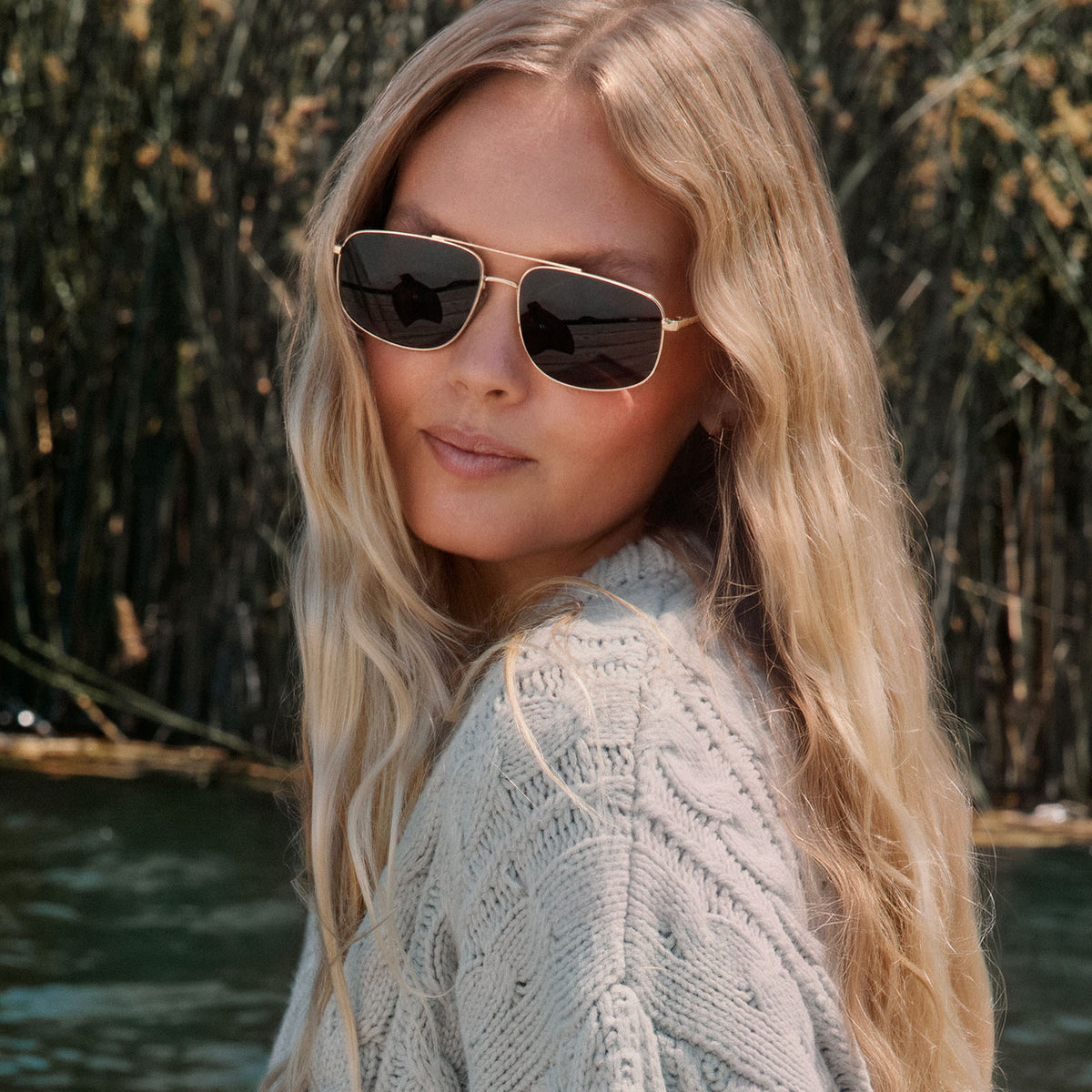 lifestyle - blonde female on a boat wearing on model - female wearing diff eyewear featuring the charley navigator sunglasses with a gold metal frame and brown polarized lenses front view
