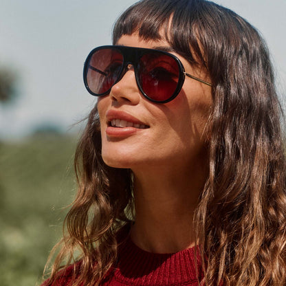lifestyle - female outdoors wearing diff eyewear cleo oversized aviator sunglasses with a black frame, gold temples and brown gradient lenses angled view