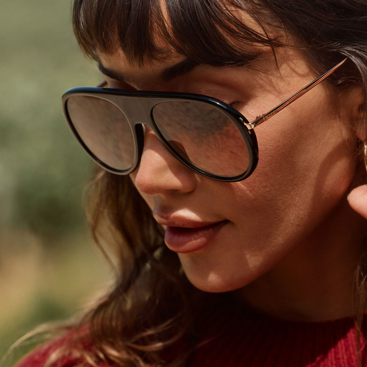 lifestyle - female outdoors wearing diff eyewear cleo oversized aviator sunglasses with a black frame, gold temples and brown gradient lenses angled view