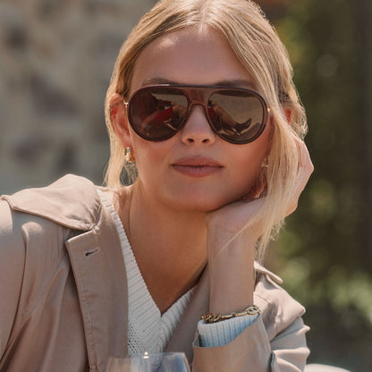 lifestyle - blonde female wearing diff eyewear cleo oversized aviator sunglasses with a dark cherry lacquer red frame, gold temples and grey gradient polarized lenses front view