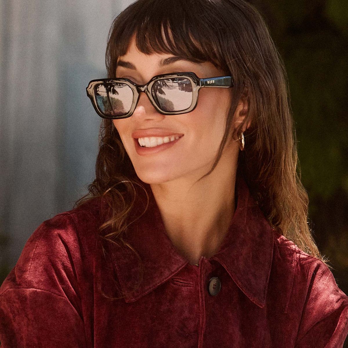 lifestyle - female wearing diff eyewear gwynn square sunglasses with a black acetate frame and light blue tint lenses front view