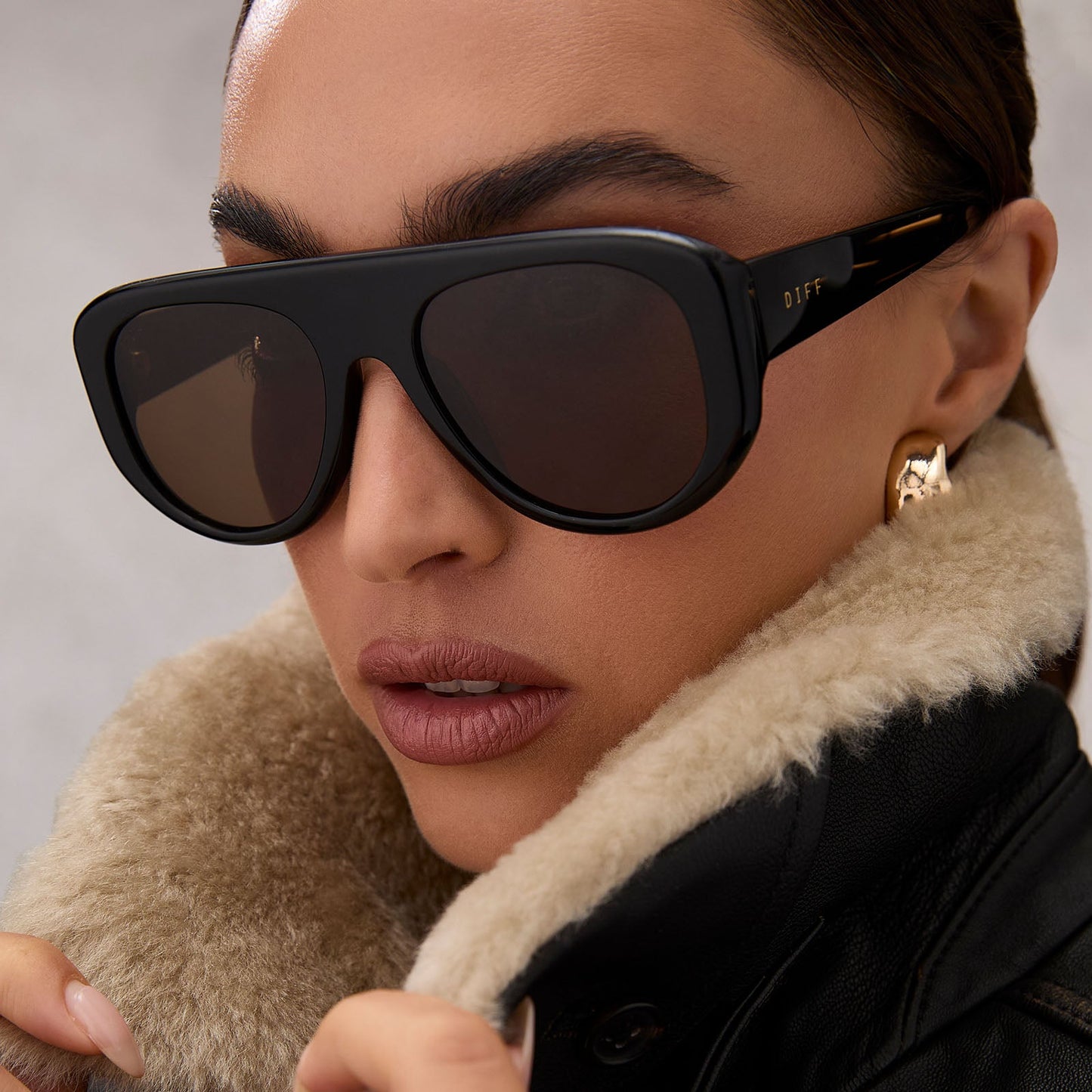 on model - female wearing diff eyewear featuring the morgan shield sunglasses with a black frame and brown lenses angled view