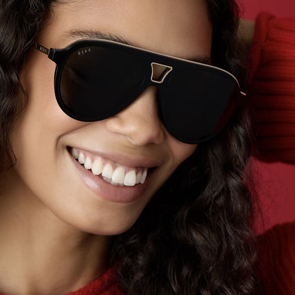 on model - female wearing diff eyewear wholesale tosca iii aviator sunglasses with a black and gold trim frame and grey lenses front view