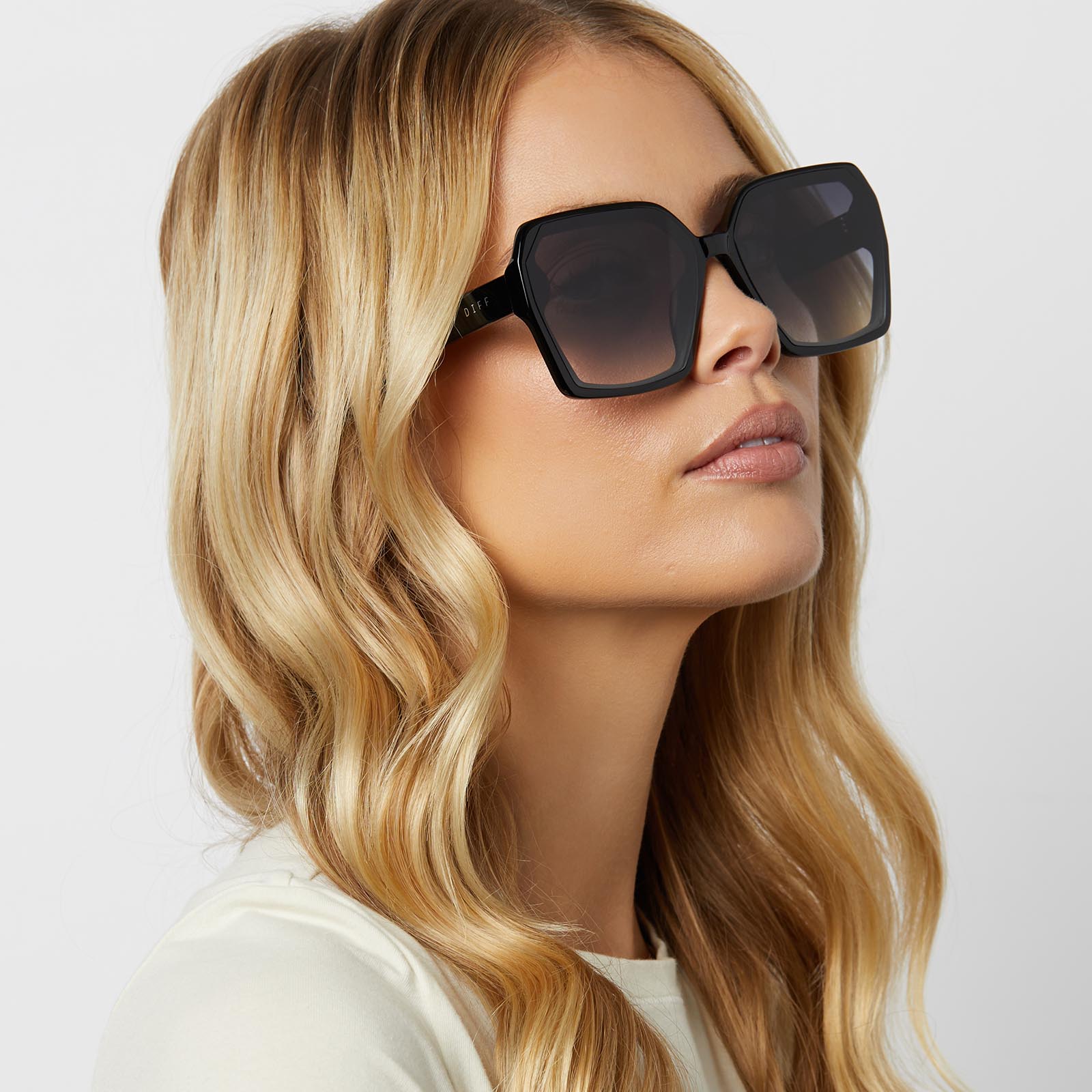 on model - blonde female wearing diff eyewear featuring the presley square sunglasses with a black frame and grey gradient lenses angled view