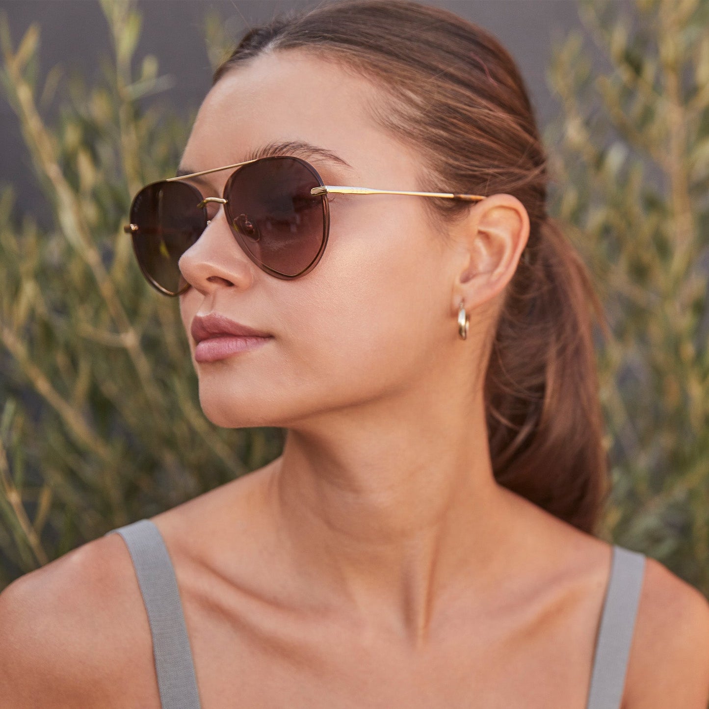 lifestyle - female model wearing lenox gold frame with sea tortoise tips and brown gradient lens sunglasses