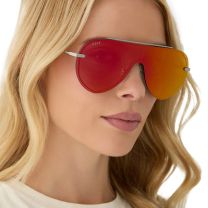 on model - female wearing diff eyewear featuring the imani shield sunglasses with a gunmetal frame and red hot summer mirror lenses angled view