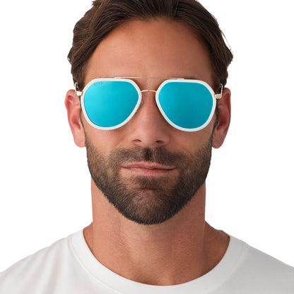 on model - male wearing diff eyewear featuring the joey round sunglasses with a snowbound & gold metal frame with blue mirror lenses front view